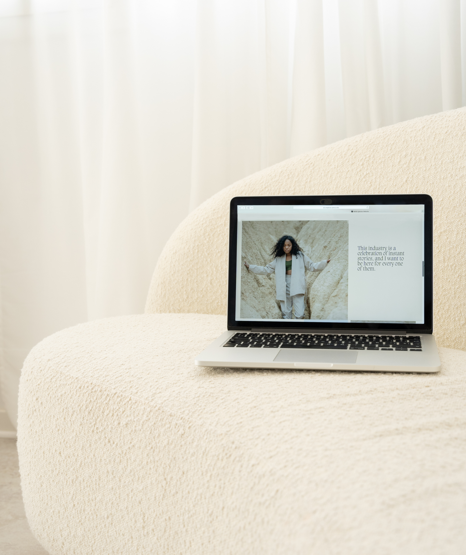 Laptop open to a web page sitting on a neutral couch with white curtains in the background