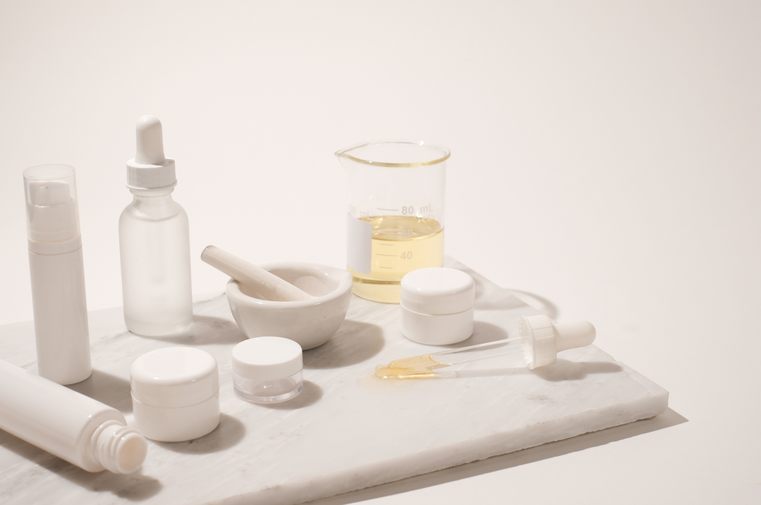 Neutral product containers sitting on a marble cutting board with a white background