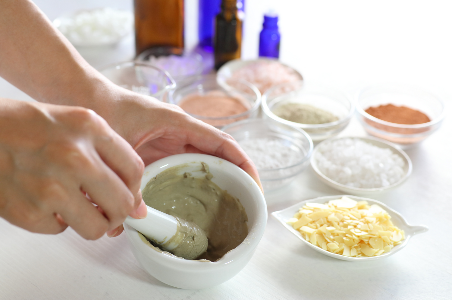 Model mixing ingredient with ingredients in dishes and product containers in the background