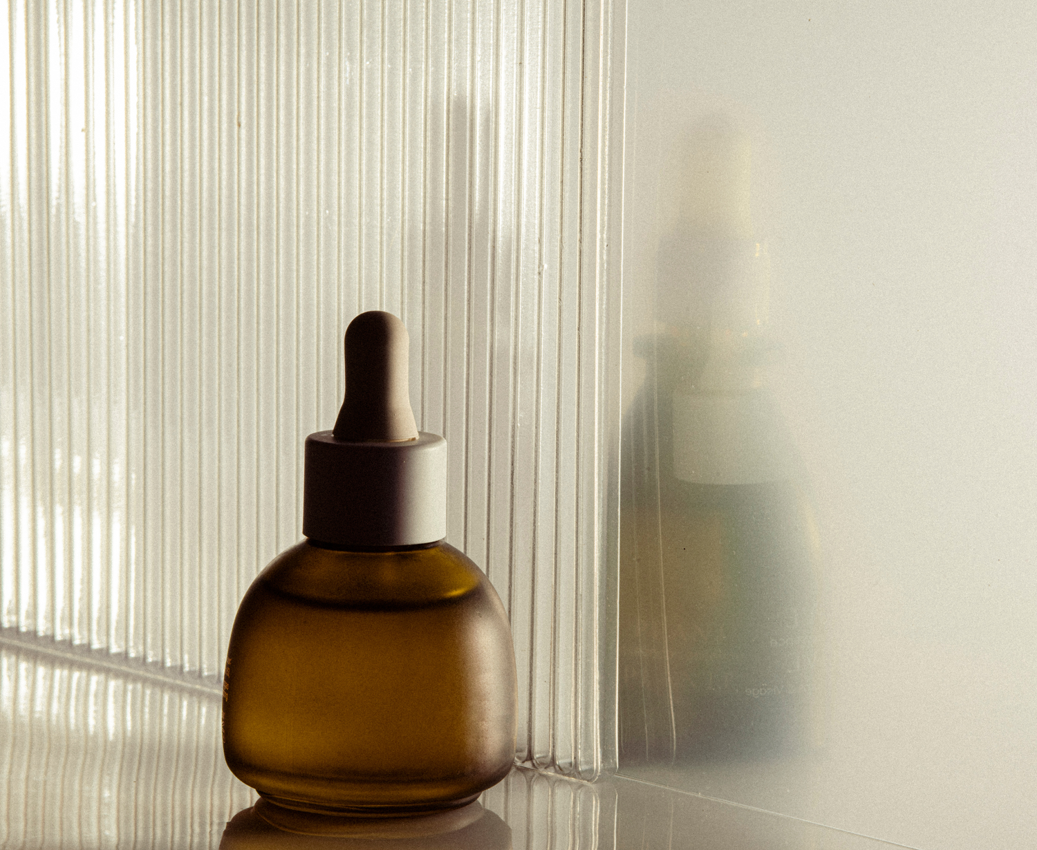 Amber dropper bottle in front of a ridged glass pane