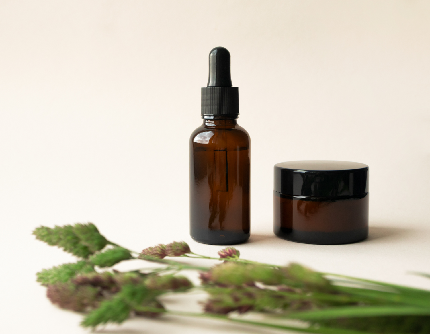 Two glass products with green grassy ingredients laying in front of them
