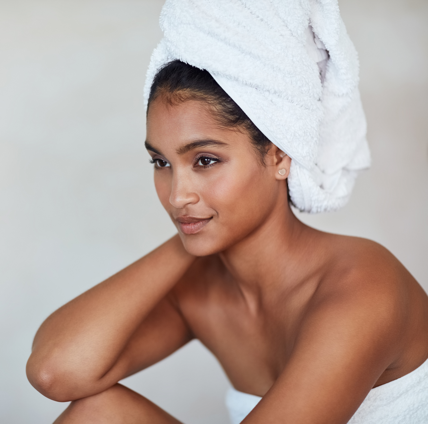 Model sitting in a towel with hair up in another towel