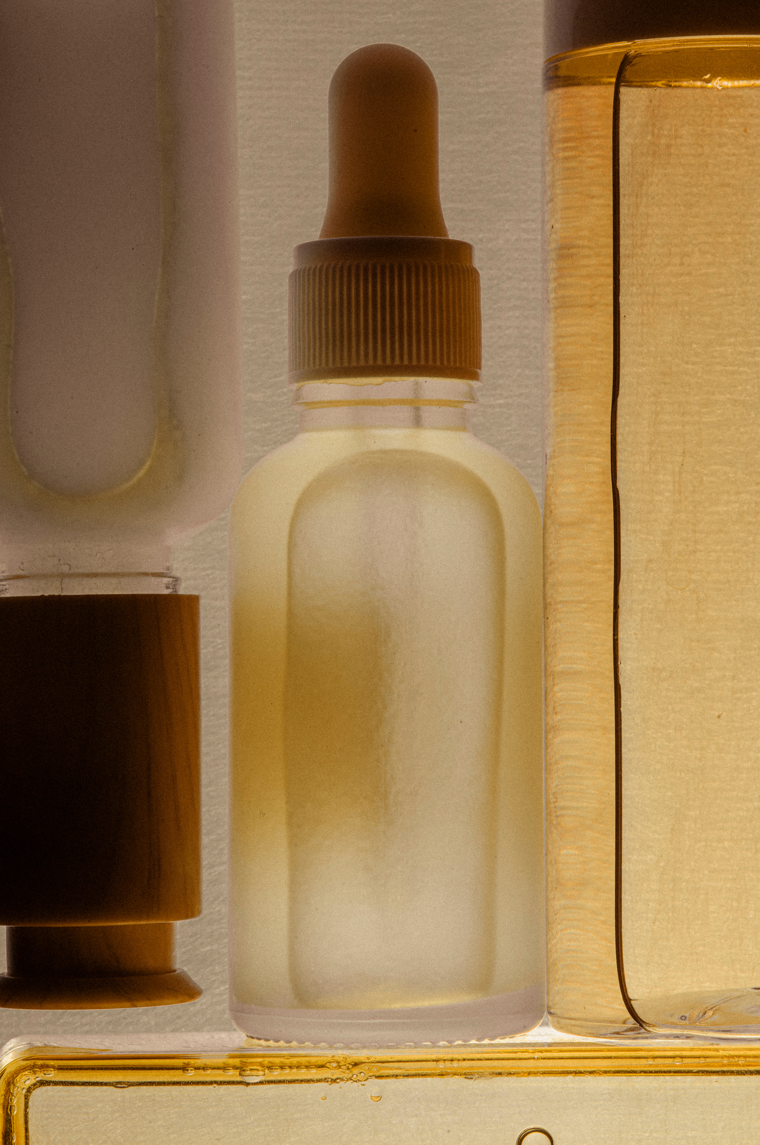Glass product bottles with a yellow hue on a textured cream background