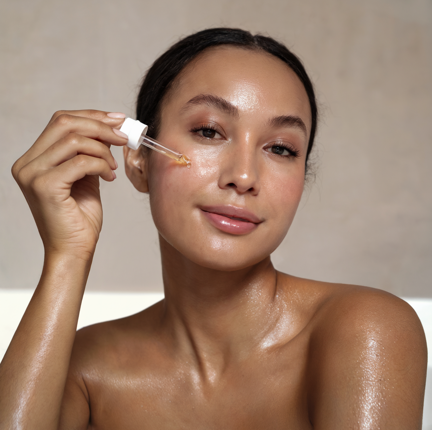 Model holding a serum dropper up to cheek