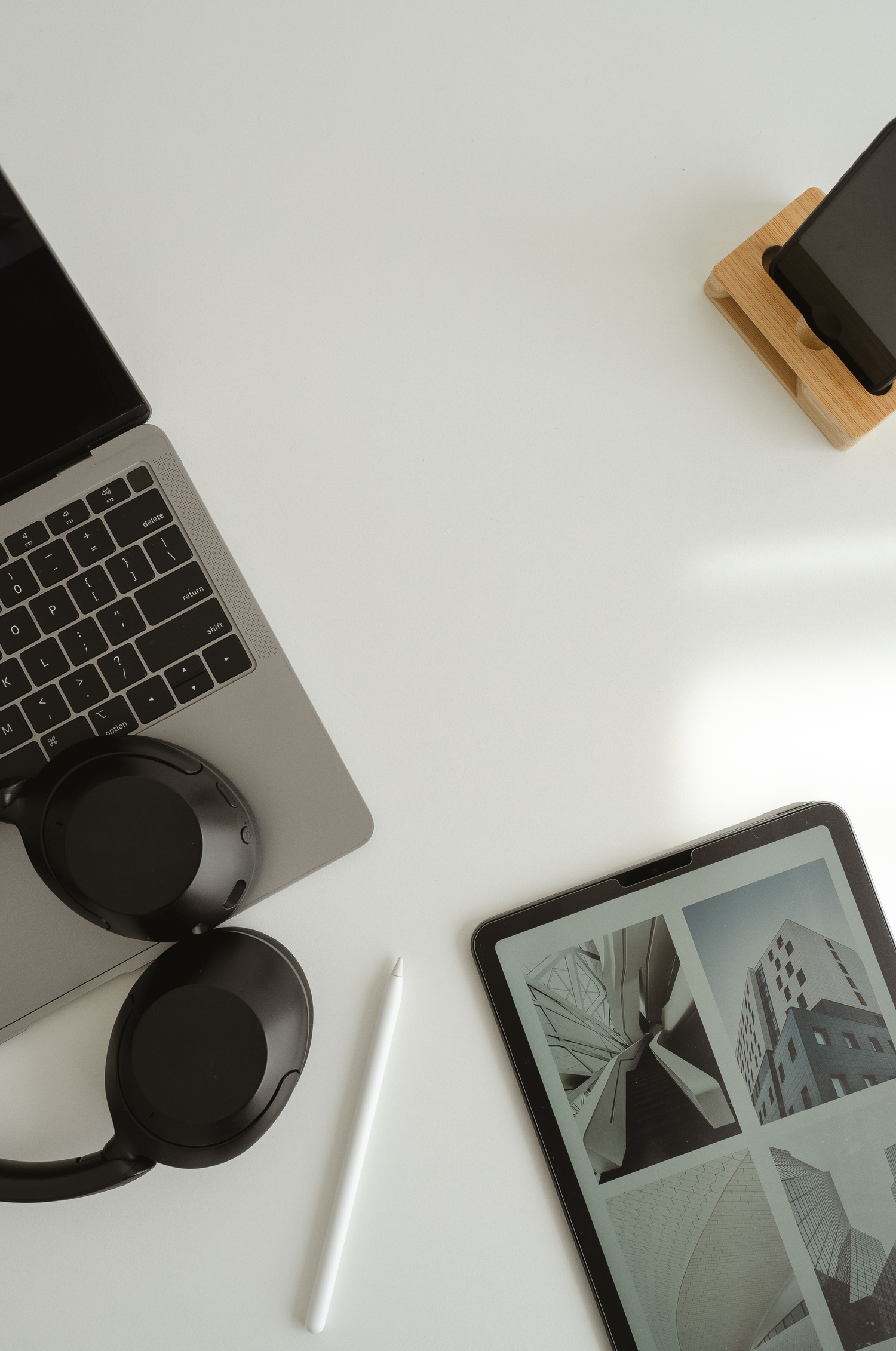 Laptop, Apple Pencil, iPad, headphones and iPhone on a white desk