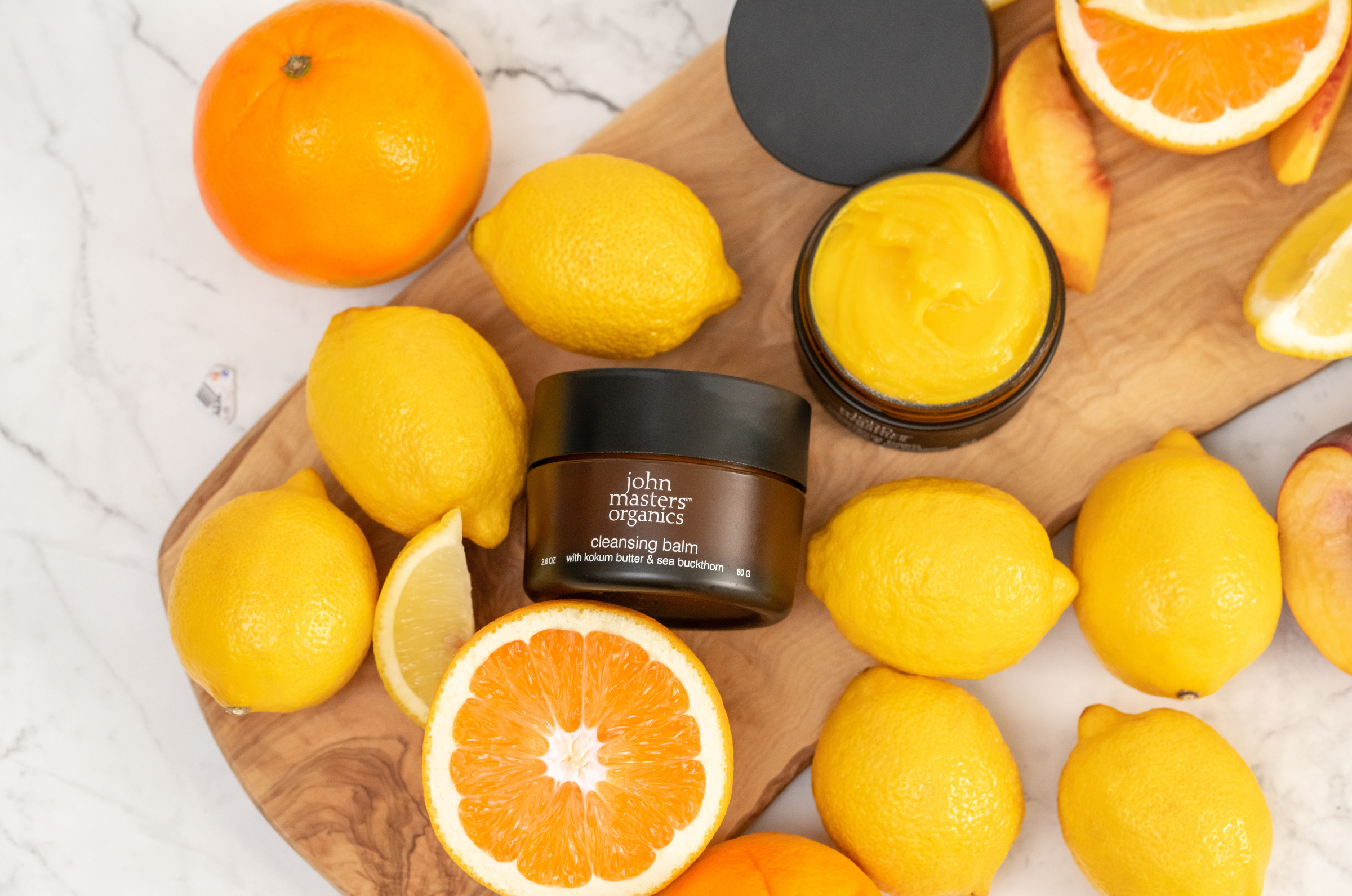 John Masers Organics Cleansing Balm on a cutting board with lemons and orange slices