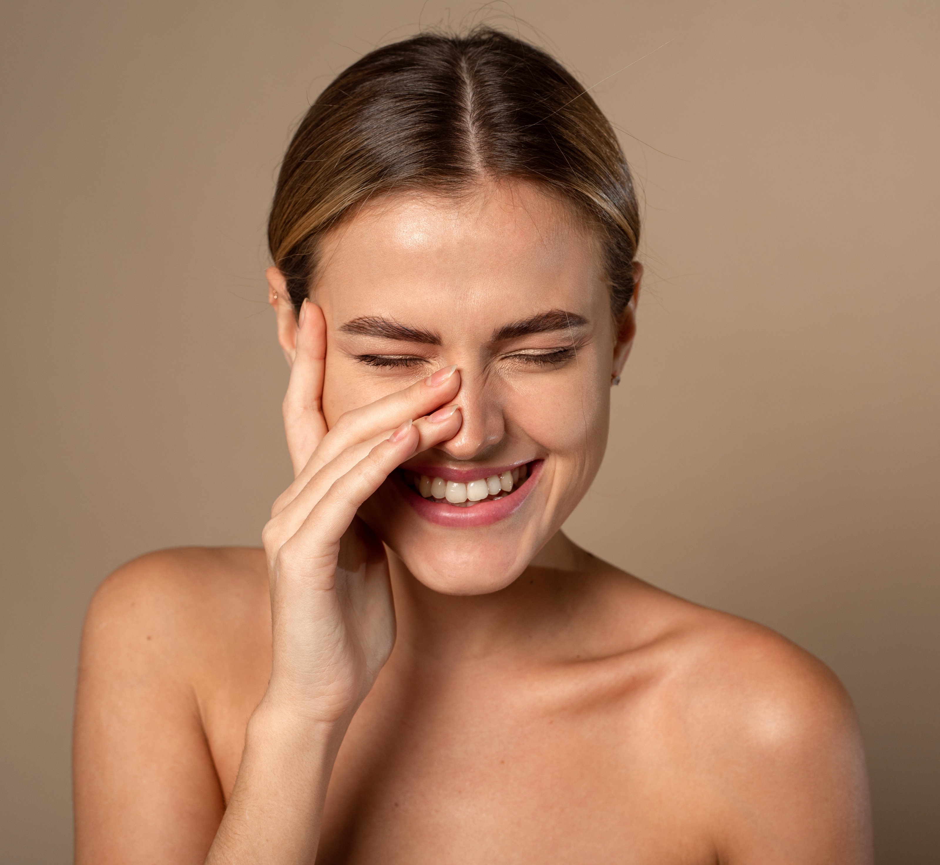 Model laughing with hand on bare face