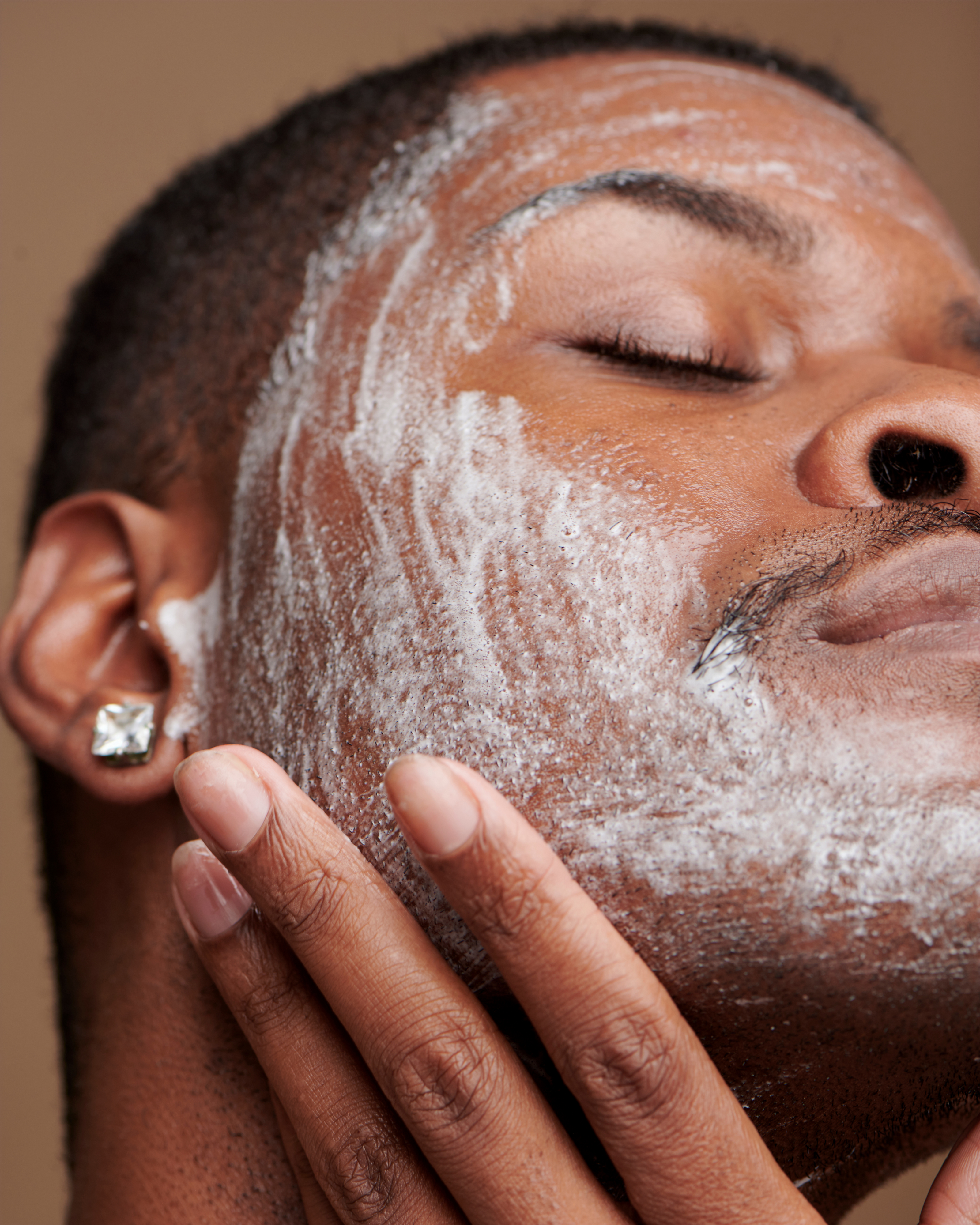 Model applying foaming face wash to skin