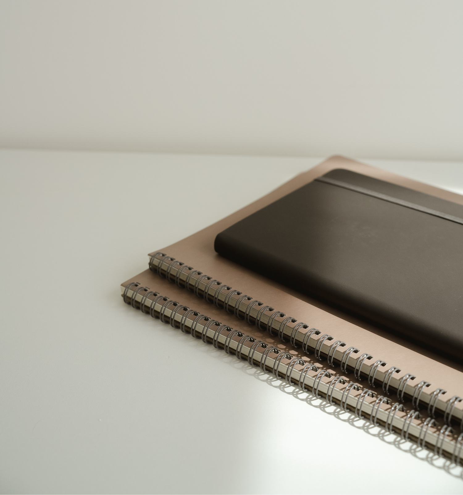 Stack of three notebooks on a white desk
