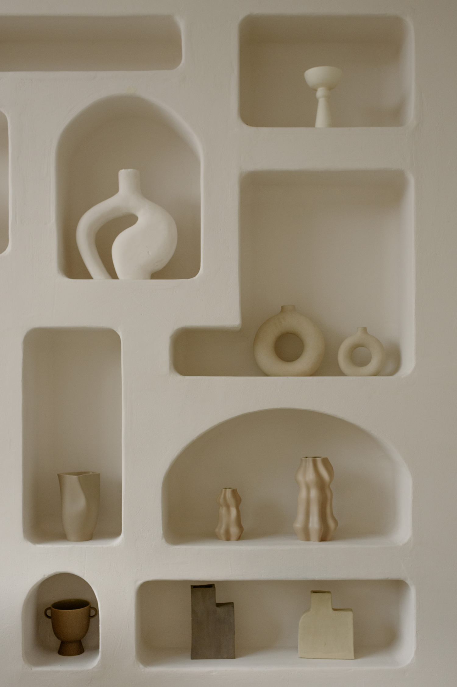 Cream shelves in organic shapes with aesthetic, neutral vases on the shelves
