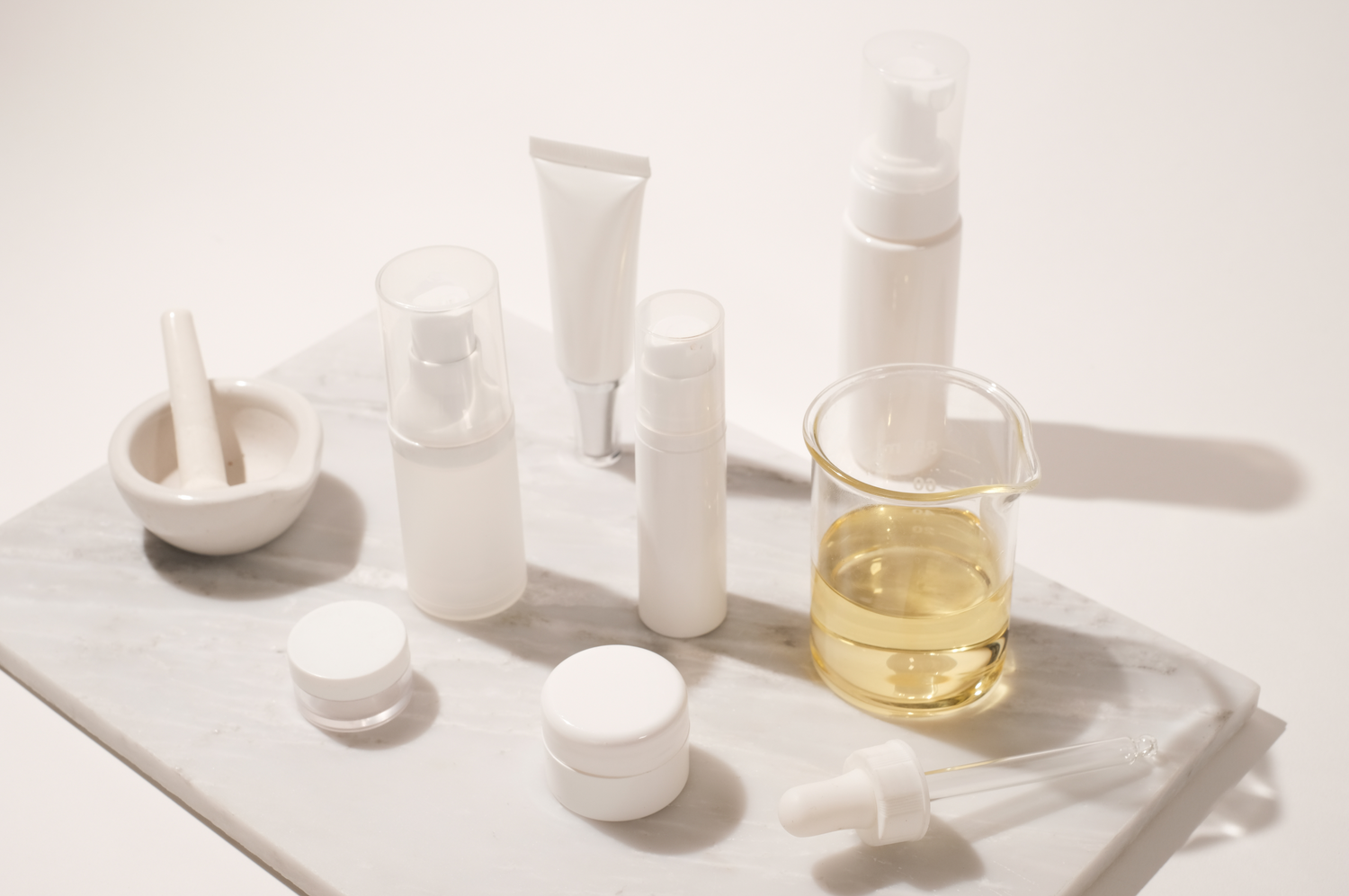 Neutral product containers sitting on a marble cutting board with a white background