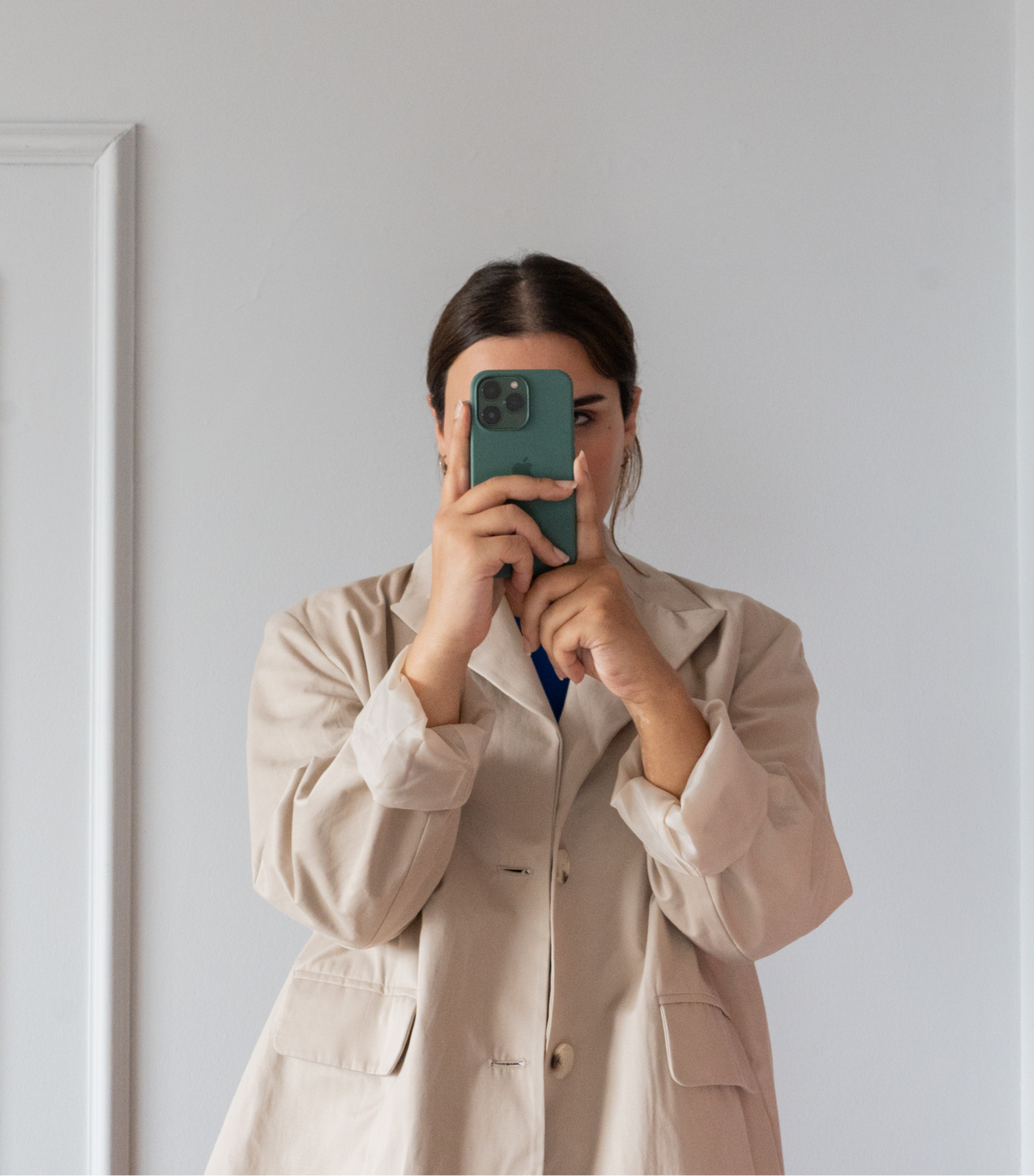 Model in a neutral blazer taking a mirror selfie